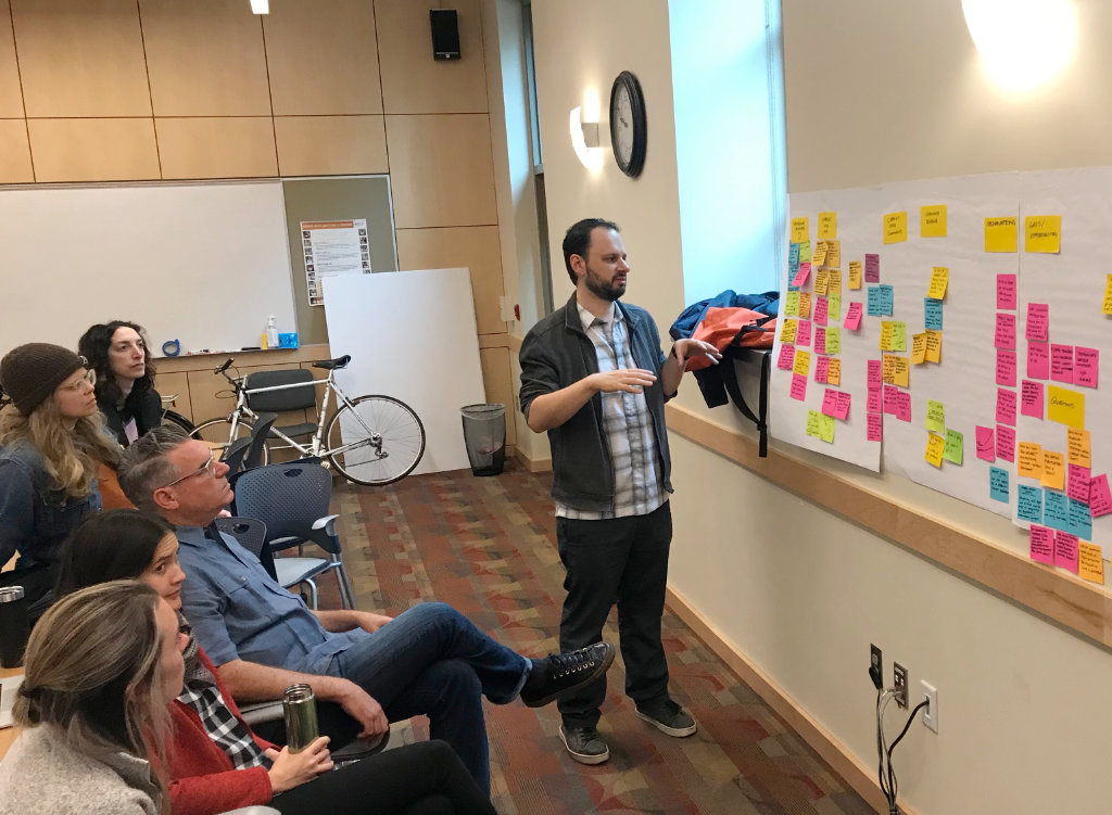 Peter standing in front of a whiteboard pointing at diagrams